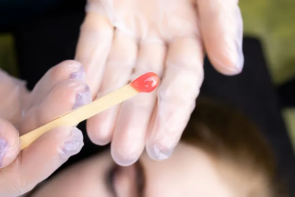 there is wax on a wooden stick to remove excess hairs from the eyebrows