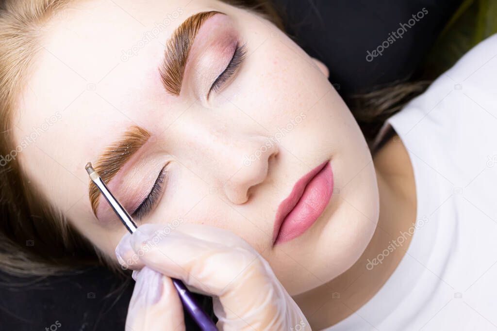 the eyebrows of the model are applied with a thick layer of paint for coloring the hairs after the lamination procedure with compounds
