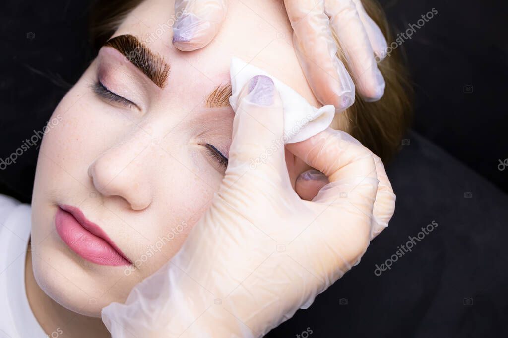 in the hands of the master is a cotton sponge with which he removes the remnants of paint from painted eyebrows