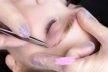 Kaplama işleminden sonra, kaşların yakın çekimi, ana cımbız kılları koparmak için