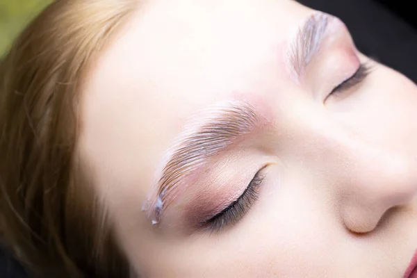 a close-up of the eyebrows of the model on which the procedure of long-term eyebrow styling is performed, laminating compositions are applied to the eyebrows of the models
