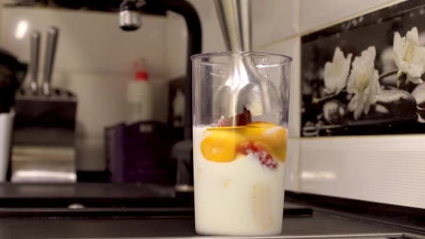 Смешивание молочного коктейля с клубникой и бананом с блендером — стоковое видео