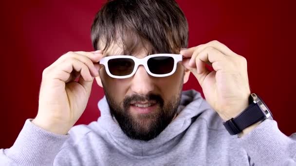Ein Mann mit Bart setzt für einen Film eine weiße Brille auf und beginnt zu tanzen — Stockvideo