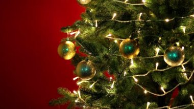 Kırmızı arka planda parlayan bir çelengi olan Noel ağacı.