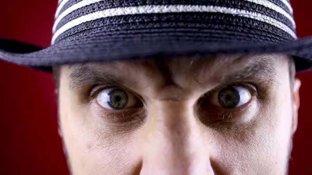 Κοντινό πλάνο ενός άνδρα μάτια σε ένα μαύρο καπέλο που φαίνεται θυμωμένα κάτω από τα φρύδια του — Αρχείο Βίντεο