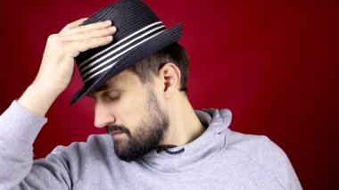 Yan duran sakallı bir adam siyah bir şapka takıyor.