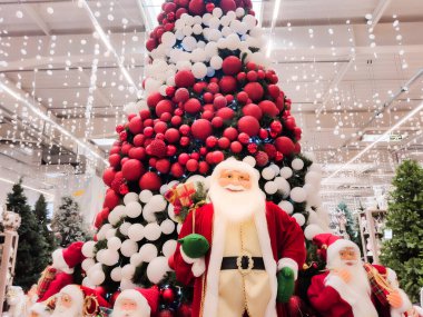 Noel Baba bebeği indirimde. Alışveriş merkezindeki Noel ağacının altında.