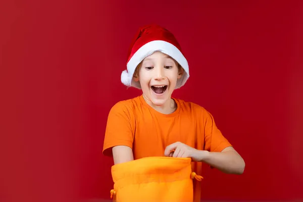 Menino Feliz Chapéu Papai Noel Enfiou Mão Saco Presente Amarelo — Fotografia de Stock