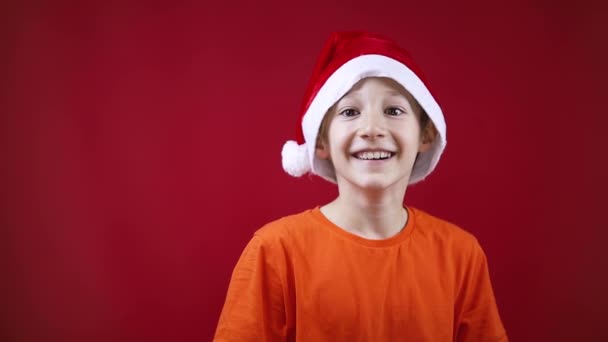 Een jongen in Santas Kerstmuts lacht naar de camera — Stockvideo