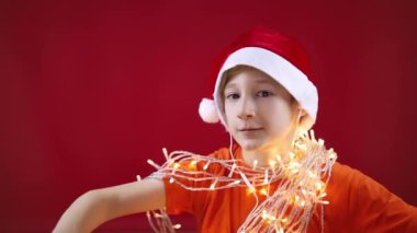 Noel Baba şapkalı ve boynunda parlak çelenkler olan komik bir çocuk. 