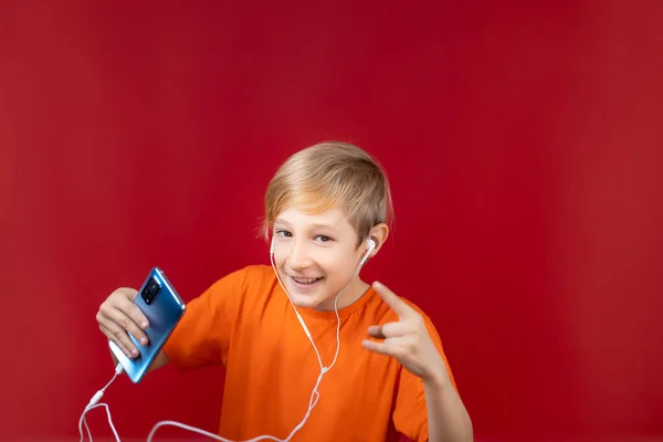 Lächelnder Junge Auf Rotem Grund Hält Ein Blaues Telefon Der — Stockfoto