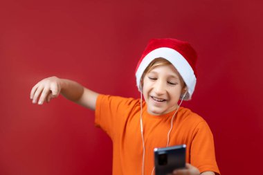 Noel Baba şapkalı bir çocuk telefonunda Noel mesajı görmüş ve çok mutlu olmuş.
