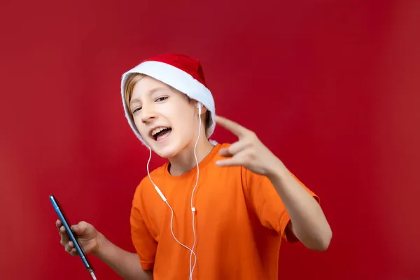 Niño Alegre Sombrero Santa Muestra Gestos Cámara Mientras Escucha Música — Foto de Stock