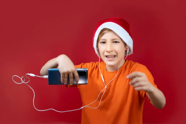 Menino Fundo Vermelho Chapéu Natal Papai Noel Caretas Gestos Enquanto — Fotografia de Stock