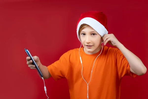 Gutt Gul Skjorte Rød Nissehatt Holder Telefon Hendene Hører Musikk – stockfoto