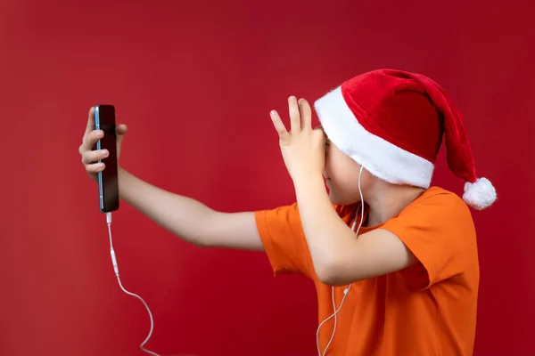 Auf Rotem Weihnachtshintergrund Ein Junge Gelben Shirt Hält Ein Handy — Stockfoto