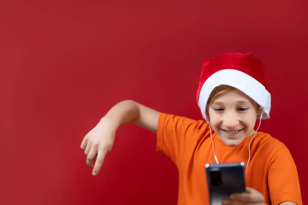 Ein Junge Mit Weihnachtsmütze Hält Ein Telefon Vor Sich Und — Stockfoto