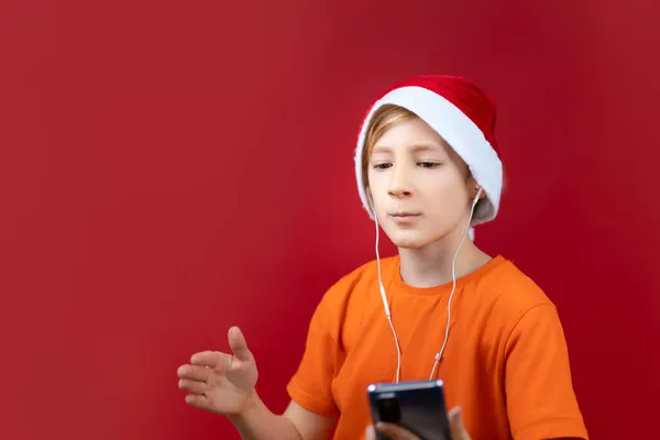 Egy Mikulás Sapkás Fiú Egy Telefont Tart Maga Előtt Karácsonyi — Stock Fotó