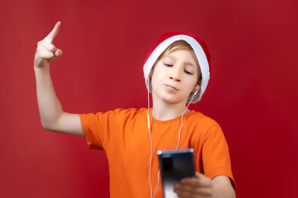 Jongen Kerstmuts Van Kerstman Houdt Telefoon Voor Zich Kijkt Ernaar — Stockfoto