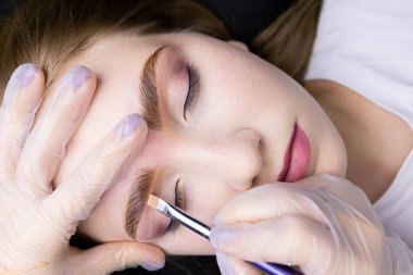 Renklendirme ve düzeltmeden sonra güzel lamine kaş yakın plan, usta bir fırça ve tonlama kremi uygular