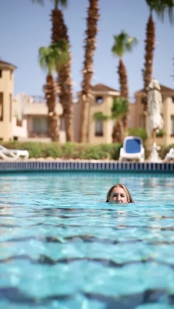Hermosa mujer nada en la piscina contra el fondo de palmeras — Vídeo de stock