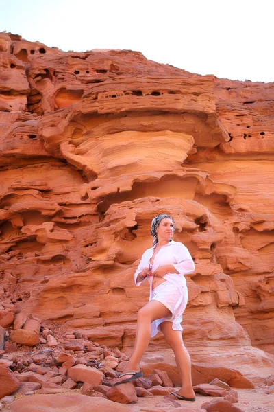 一个穿着白衣的女游客 头顶着头巾 站在岩石的背景下 — 图库照片