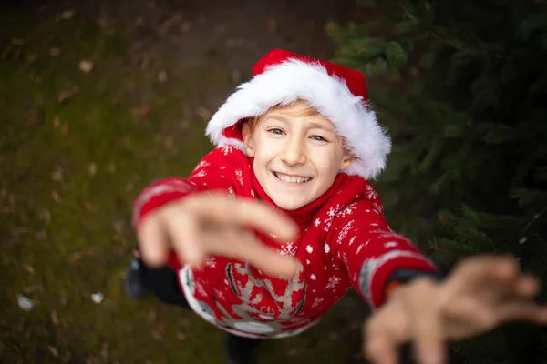 크리스마스 공원에서 산타클로스 모자를 크리스마스 스웨터를 카메라 — 스톡 사진
