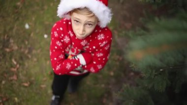 Noel geyiği ve Noel şapkalı kırmızı örülü Noel süveteri giyen çocuk.