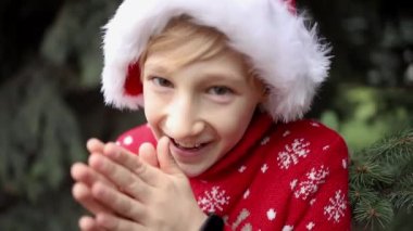 Noel geyiği ve Noel şapkalı kırmızı örülü Noel süveteri giyen çocuk.