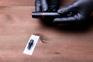 Siyah eldivenli bir makyaj sanatçısının ellerinde dövme kalemi var.