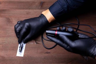 Siyah tıbbi eldivenli daimi makyaj ustasının elleri dövmesi için tek kullanımlık bir fişek aldı.