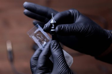 Siyah tıbbi eldivenli kalıcı makyaj sanatçısının elleri paketten tek kullanımlık bir kartuşu çıkardı ve nazikçe iki parmağıyla tuttu.