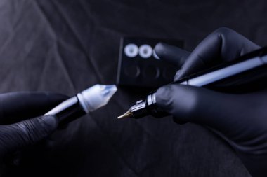 Kalıcı bir kaş makyajcısının ellerinde pigmentli bir şişe ve dövme makinesi var.