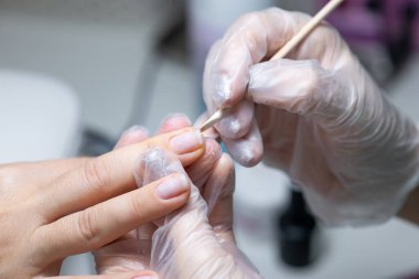 Tırnak bakım ustası manikür yapıyor. Tırnak altlarındaki toprağı tahta bir sopayla temizliyor.