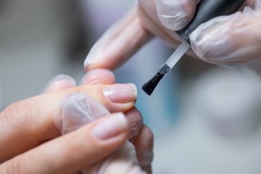 Manikür yapan manikür ustası renkli jel cilası için tırnağı hazırlar.