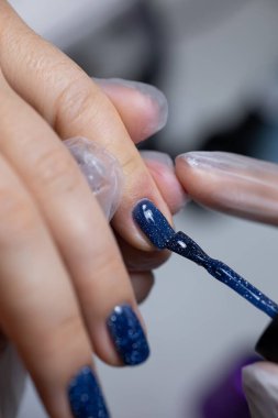 Manikür ustası, tırnak cilasına güzel bir jöle sürme prosedürünü gerçekleştirir.