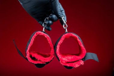 Elleri siyah eldivenli, elleri kelepçeli, bdsm seks oyunları için kırmızı kemerli