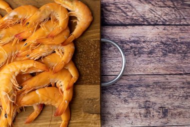 Tahta bir masanın üzerinde karidesli ahşaptan yapılmış bir tabak var.