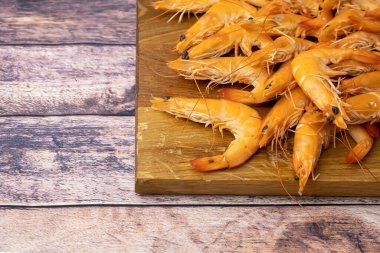 Tahtadan yapılmış tezgahta duran kaynamış karidesin üst görüntüsü.