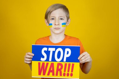 Üzerinde yazıtların savaşı durdurduğu Ukrayna bayrağının posteri olan bir çocuk.