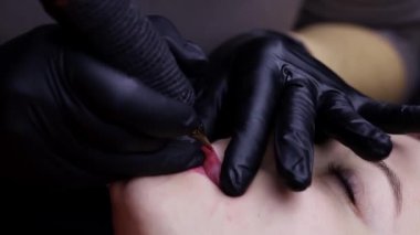 Modelin dudaklarındaki usta dudak dövmesi yapar ve dudakların kalıcı makyajını yapar.