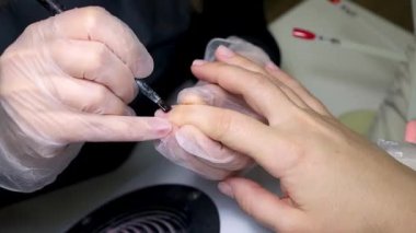 Manikür ustası fırçayla koruyucu oje sür.