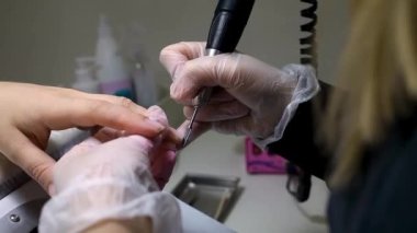 Manikür ve pedikür ustası manikür makinesi ile manikür yapıyor.