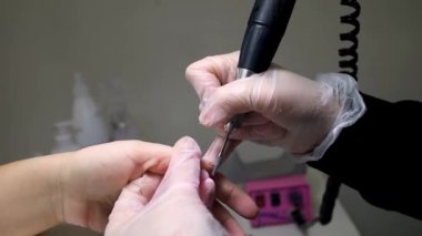 Manikür ve pedikür ustası manikür makinesi ile manikür yapıyor.