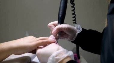 Manikür ve pedikür ustası manikür makinesi ile manikür yapıyor.