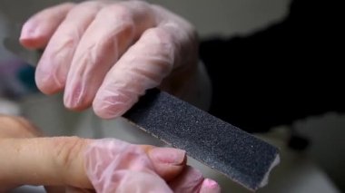 Manikür ve pedikür ustası çiviyi törpülüyor, böylece manikürü düzleştiriyor.