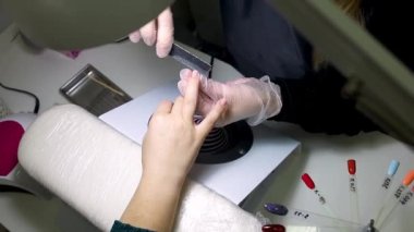 Manikür ve pedikür ustası çiviyi törpülüyor, böylece manikürü düzleştiriyor.