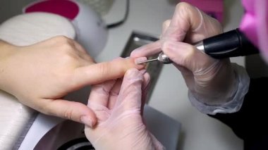 Manikür ve pedikür ustası manikür makinesi ile manikür yapıyor.