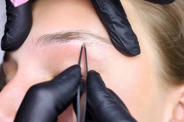 Kaşları cımbızla kapladıktan sonra istenmeyen kaş kıllarını yolmak.