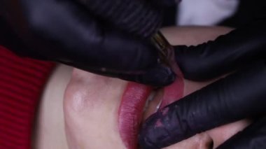 Dövme makinesi ve kırmızı pigment kullanarak dudakların kalıcı makyajı için prosedürü kapat